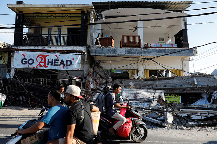 People ride motorcycles along a street next to collapsed shops after an earthquake hit on Sunday in Pemenang, Lombok Island, Indonesia, August 7, 2018.