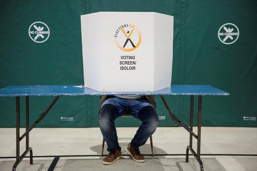 A voter sits behind a voting screen while marking their vote during the New Brunswick provincial election in Dieppe, N.B. on Monday, September 24, 2018.
