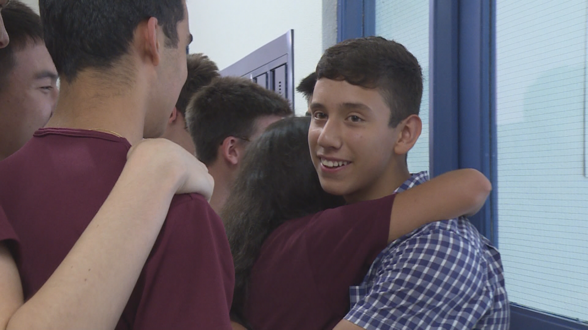 Alois Orozco is hugged by students at Royal West Academy.