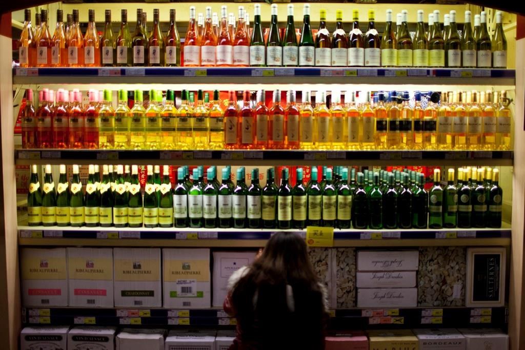 FILE- In this Nov. 27, 2012 file photo, a customer checks bottles of imported wine at a supermarket in Beijing.