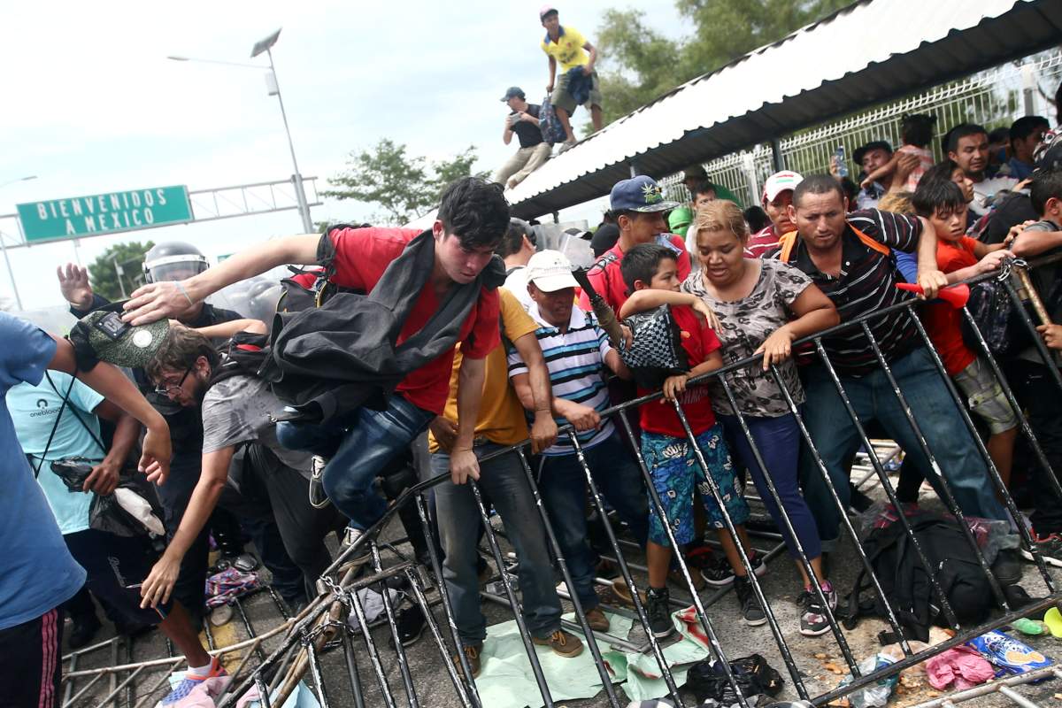 Honduran migrants, part of a caravan trying to reach the U.S., storm a border checkpoint in Guatemala, in Ciudad Hidalgo, Mexico, on October 19, 2018.
