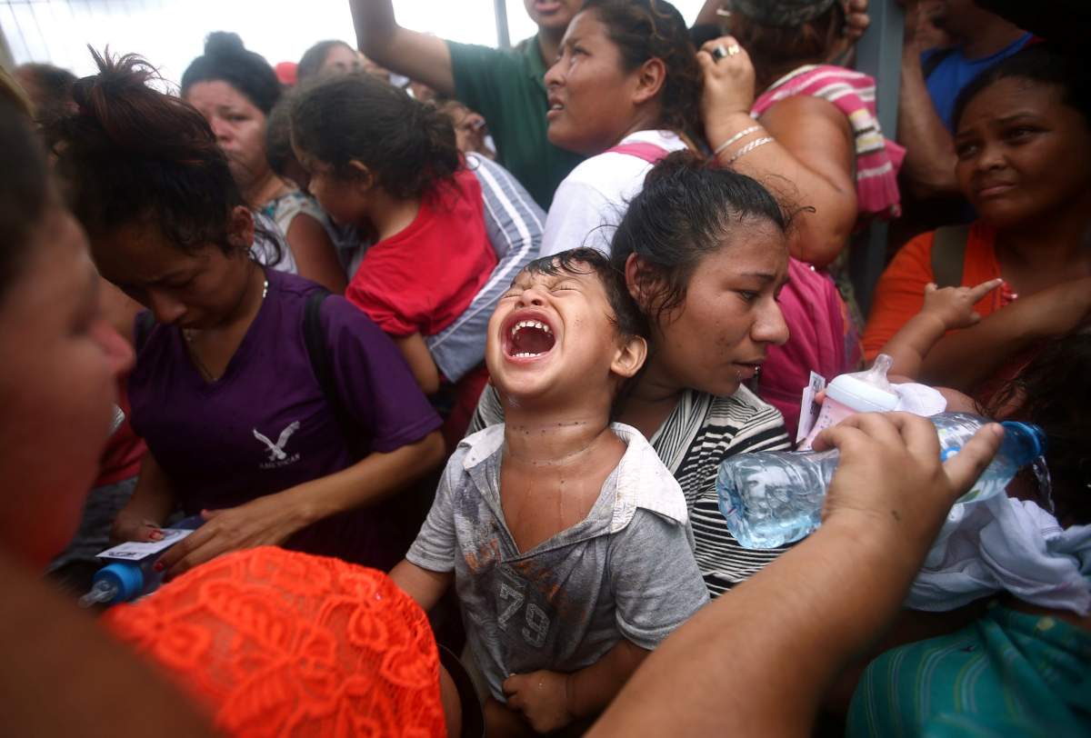 A Central American migrant, part of a caravan trying to reach the U.S., reacts as he waits to apply for asylum in Mexico at a checkpoint in Ciudad Hidalgo, Mexico.