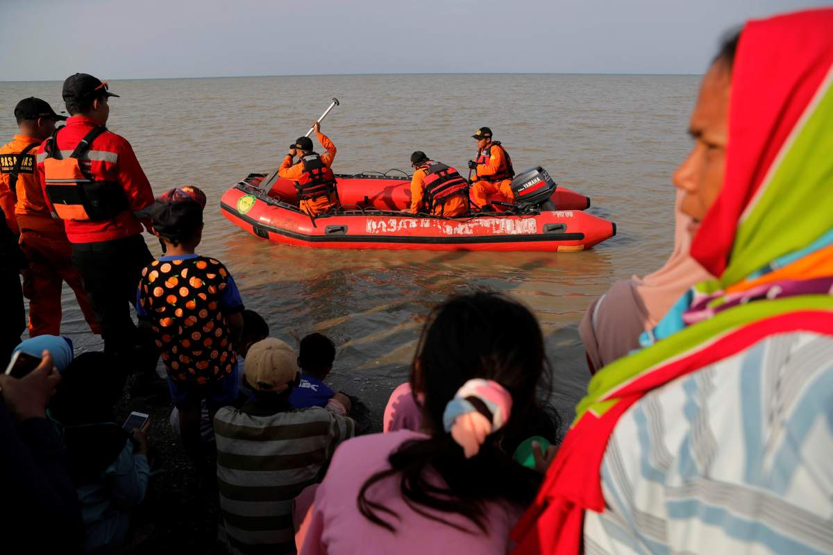 People watch rescue team members prepare the boat heading to the Lion Air, flight JT610, sea crash site off the coast of Karawang regency, West Java province, Indonesia, October 29, 2018.