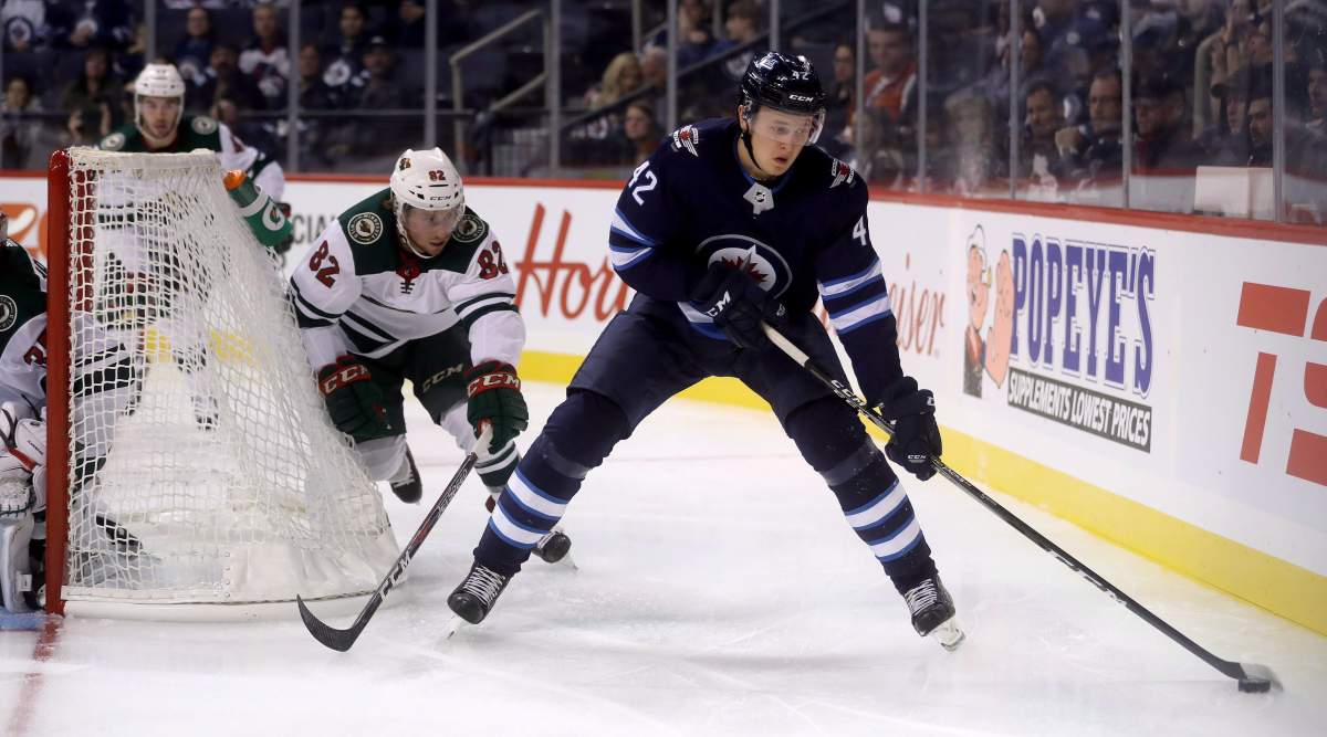 Winnipeg Jets' Kristian Vesalainen (42) carries the puck in front of Minnesota Wild's Justin Kloos (82) behind the Minnesota goal during second period preseason NHL hockey in Winnipeg, Monday, September 17, 2018. THE CANADIAN PRESS/Trevor Hagan.