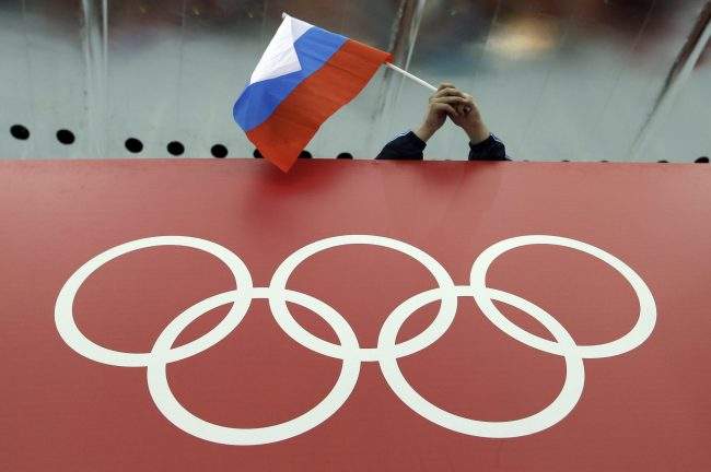 In this Feb. 18, 2014, file photo, a Russian skating fan holds the country's national flag over the Olympic rings at Adler Arena Skating Center during the 2014 Winter Olympics in Sochi, Russia. 


