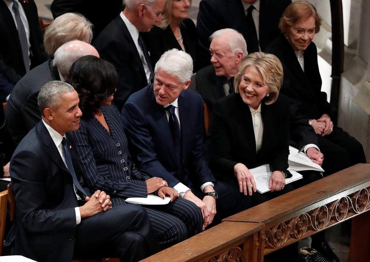 Former U.S. President Bill Clinton and former first lady and Secretary of State Hillary Clinton look over at former U.S. President Barack Obama and former first lady Michelle Obama while seated with former President Jimmy Carter and first lady Rosalynn Carter (R) prior to the state funeral.