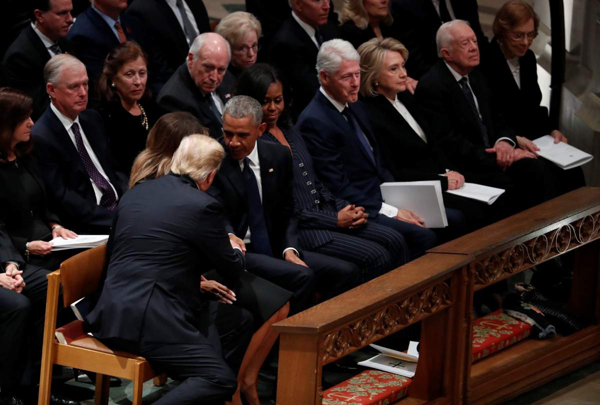 U.S. President Donald Trump reaches over to shake hands with former President Barack Obama as he takes his seat in the first row along with former first lady Michelle Obama, former President Bill Clinton and former first lady Hillary Clinton, former President Jimmy Carter and first lady Rosalynn Carter prior to the state funeral for former U.S. President George H.W. Bush at the Washington National Cathedral in Washington, U.S., December 5, 2018. REUTERS/Kevin Lamarque