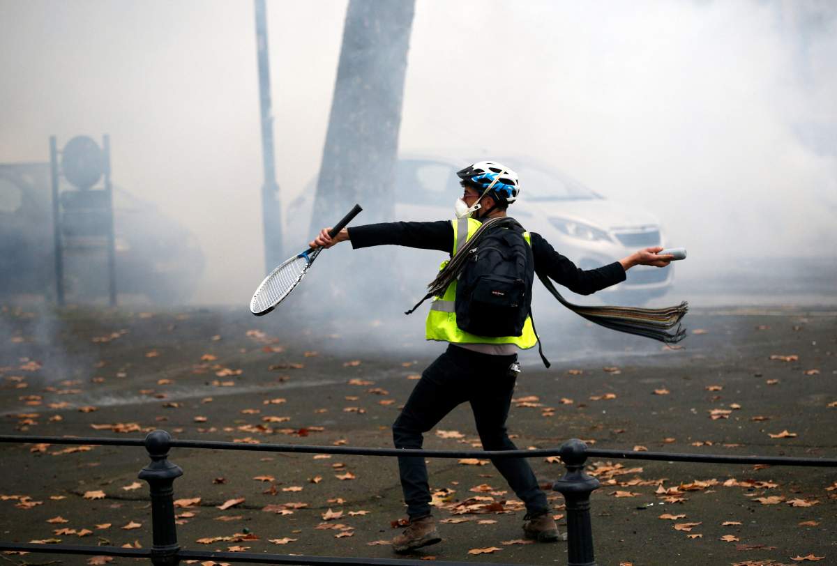 A protester wearing a yellow vest reacts to the tear-gas canisters fired by police during a demonstration of the "yellow vests" movement in Nantes, France, December 22, 2018. REUTERS/Stephane Mahe.