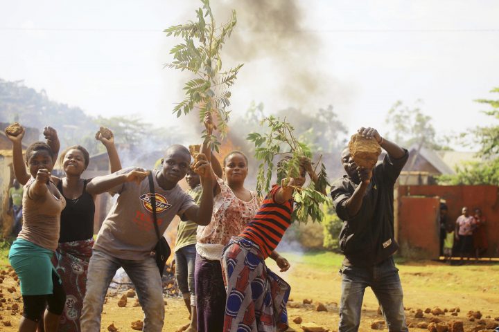 Protesters act in front of the camera after setting a burning barricade in the Eastern Congolese town of Beni Thursday Dec. 27, 2018.