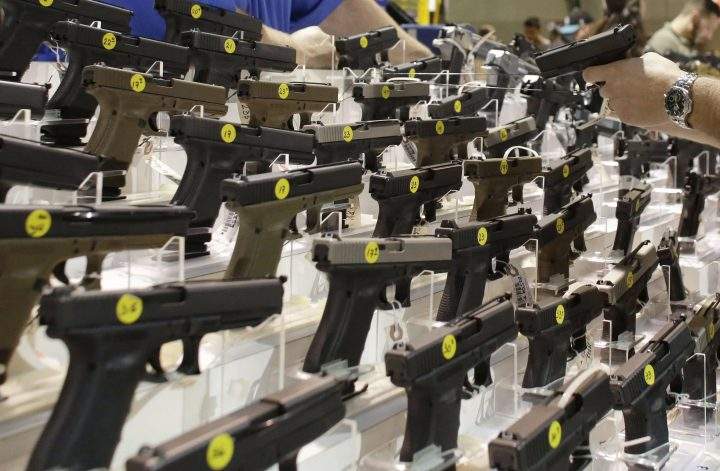 A customer looks at a pistol at a vendor's display at a gun show held by Florida Gun Shows in Miami.
