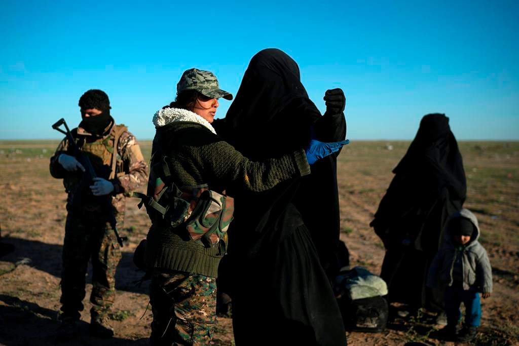 A woman is frisked by a U.S.-backed Syrian Democratic Forces (SDF) fighter at a screening area after being evacuated out of the last territory held by Islamic State militants, in the desert outside Baghouz, Syria, on March 1, 2019. (AP Photo/Felipe Dana)