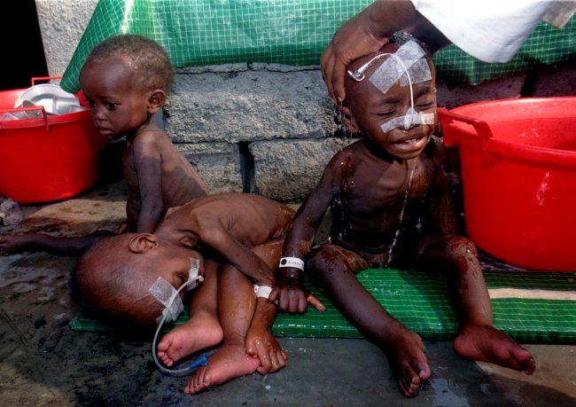 Three Rwandan orphans in medical treatment, waiting to be washed by relief worker at Ndoshu orphanage, Aug. 16, 1994.