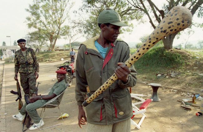 A Rwandan Patriotic Front rebel observes a nail-spiked club found near a militia checkpoint which was abandoned after the rebel victory in Kigali, Rwanda July 7, 1994.