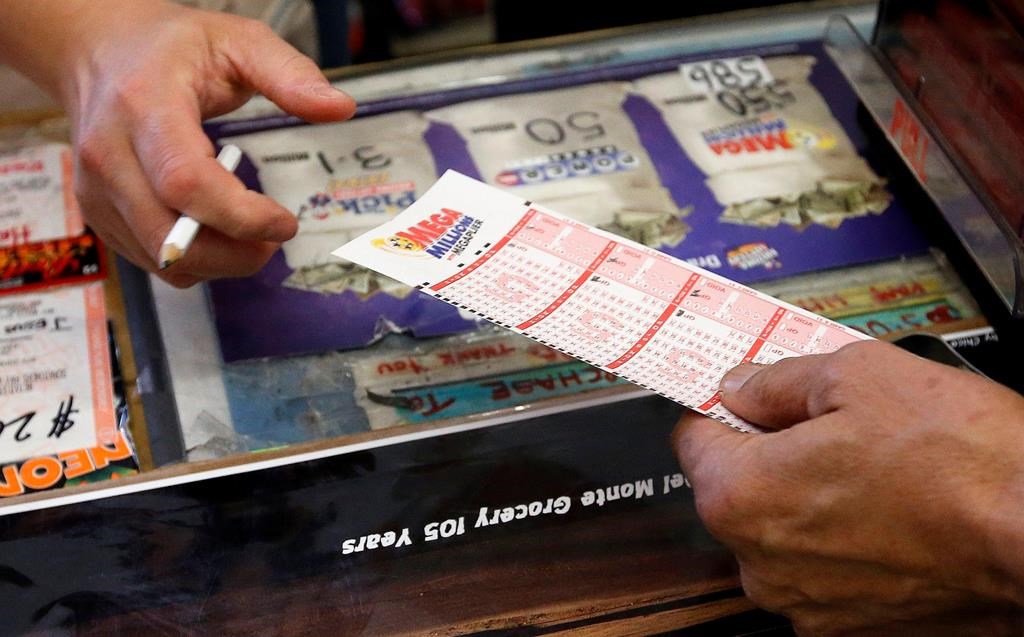 FILE - In this Tuesday, Dec. 17, 2013 file photo, Keith Ganatra, right, owner of the Del Monte Market, takes the numbers form picked by a customer, as he sells Mega Millions lottery tickets at a brisk pace in Laveen, Ariz.