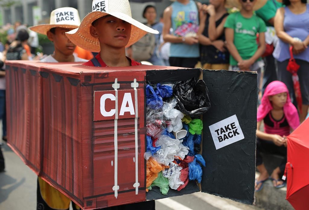Filipino environmental activists wear a mock container vans filled with garbage to symbolize the 50 containers of waste that were shipped from Canada to the Philippines two years ago, as they hold a protest outside the Canadian embassy at the financial district of Makati, south of Manila, Philippines on Thursday, May 7, 2015.