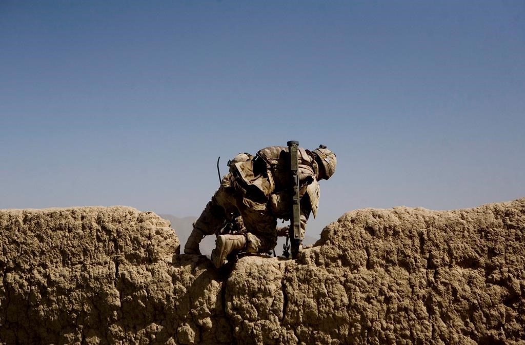 A Canadian soldier with 1st RCR Battle Group, The Royal Canadian Regiment, climbs over a wall as he patrols with his unit to find improvised explosive devices, or IEDs in the Panjwayi district, southwest of Kandahar, Afghanistan on June 6, 2010.