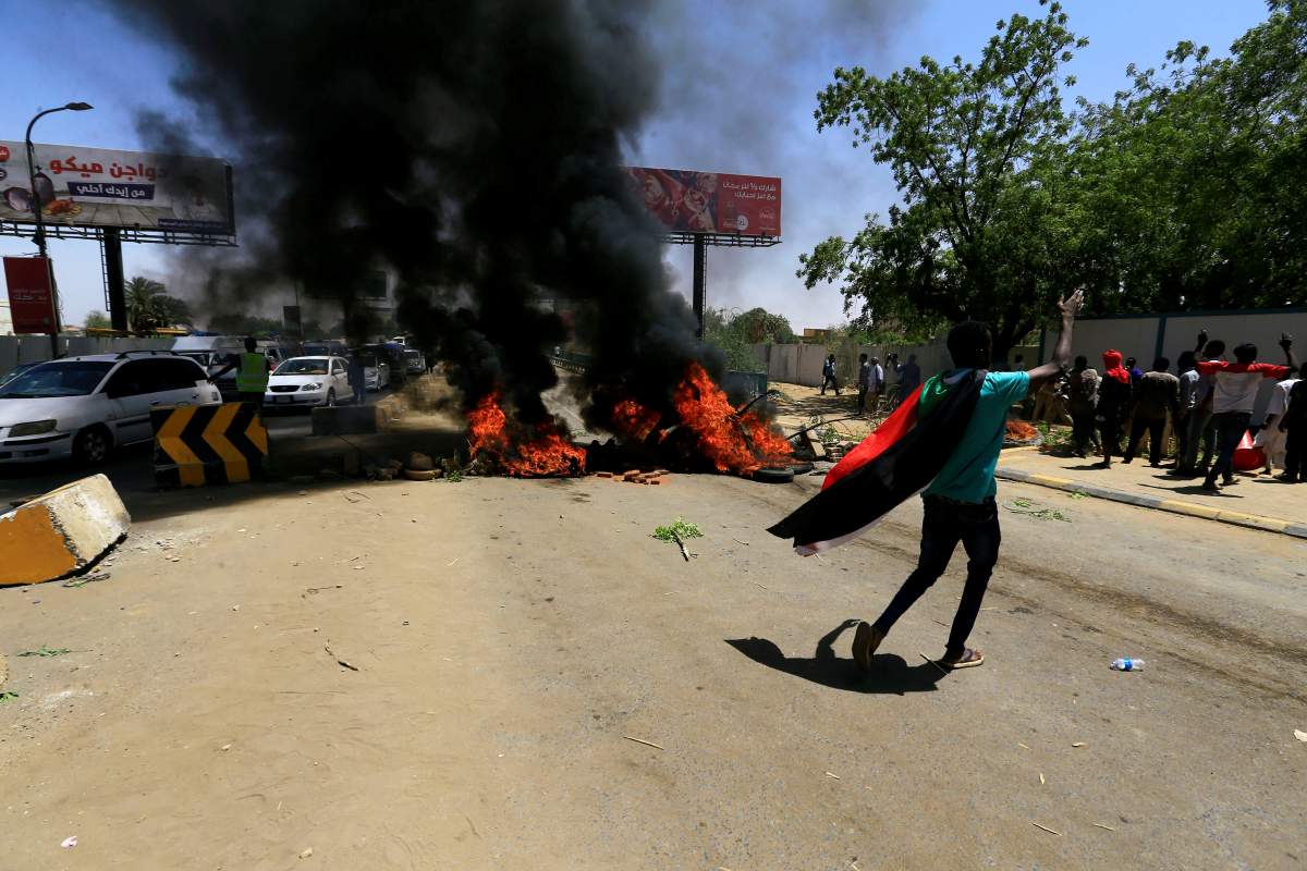 A Sudanese protester gestures as they burn tyres and barricade the road leading to al-Mek Nimir Bridge crossing over Blue Nile; that links Khartoum North and Khartoum, in Sudan May 13, 2019. 