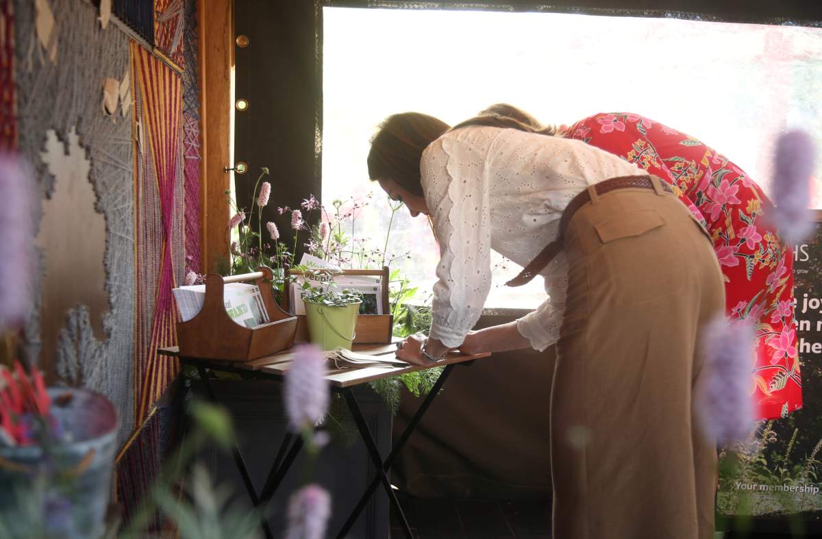 Britain’s Catherine, Duchess of Cambridge, writes a message to pin to a board during her visit to the RHS Chelsea Flower Show at the Royal Hospital Chelsea, London Britian May 20, 2019. Yui Mok/Pool via REUTERS