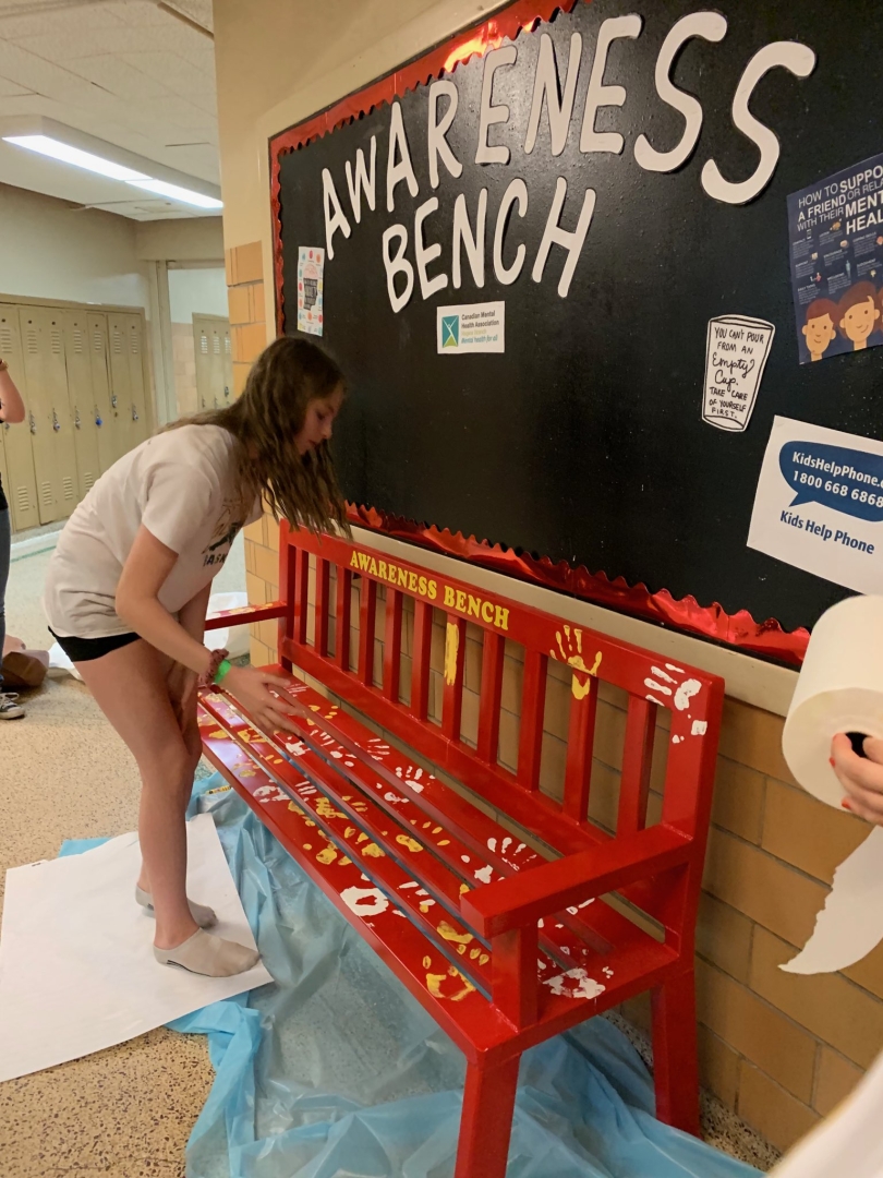 A student at Sheldon Williams Collegiate places a hand print on a newly-installed “Awareness Bench” at the school.