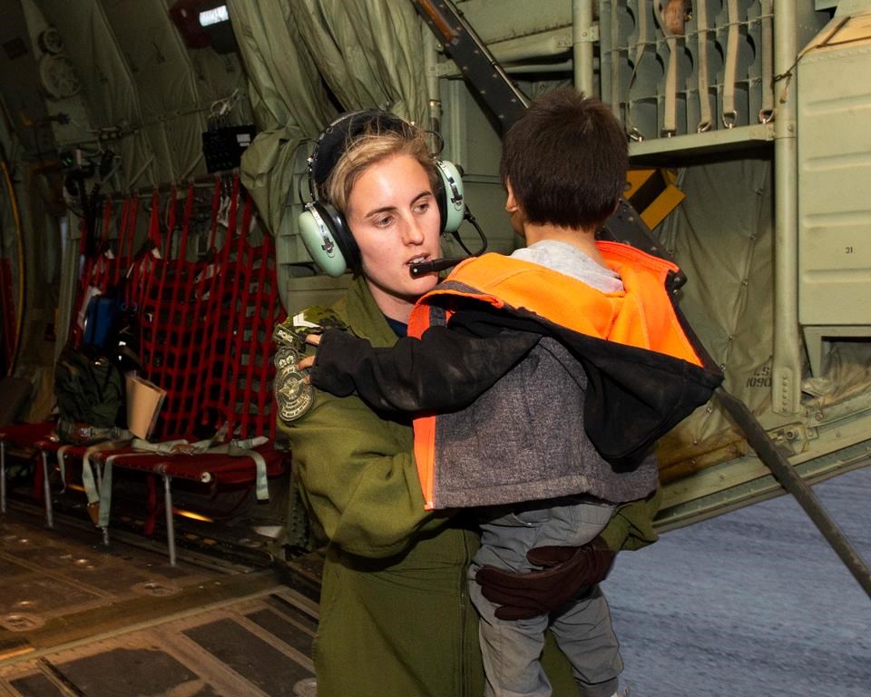 A member of the Canadian Armed Forces helps evacuate a child of the Pikangikum First Nation in Northern Ontario, as part of operation LENTUS on Thursday, May 30, 2019. Ontario's Ministry of Natural Resources says a wildfire threatening a remote Indigenous community in the province's northwest has grown several times larger.