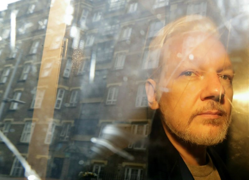 FILE - In this Wednesday, May 1, 2019 file photo, buildings are reflected in the window as WikiLeaks founder Julian Assange is taken from court.
