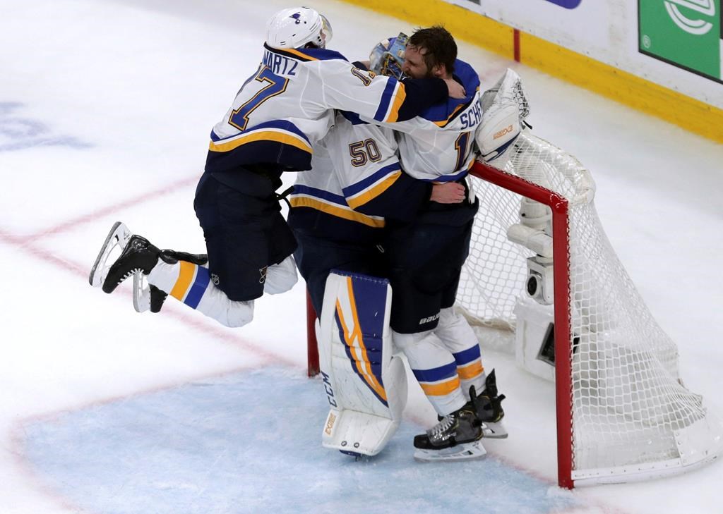 St. Louis Blues' Jaden Schwartz, left, and Brayden Schenn, right, mob goaltender Jordan Binnington to celebrate their win over the Boston Bruins in Game 7 of the NHL hockey Stanley Cup final, Wednesday, June 12, 2019, in Boston.