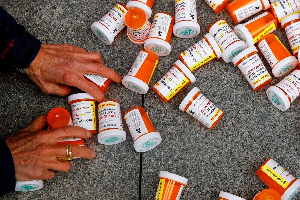 In this Friday, April 5, 2019, file photo, a protester gathers containers at an anti-opioid demonstration in Washington, D.C. Saskatchewan's provincial auditor has tabled a new report that calls for the Ministry of Health to pay closer attention to how highly-addictive opioids are leaving pharmacies. THE CANADIAN PRESS/AP/Patrick Semansky.