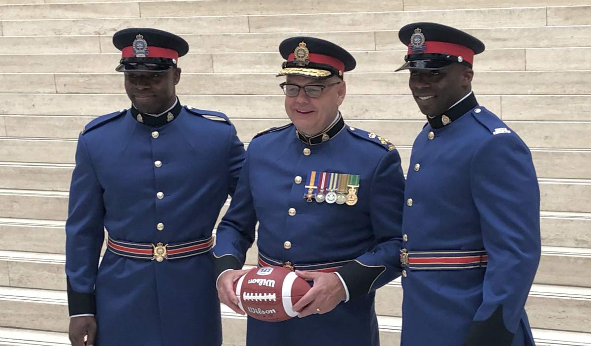 Former CFL players Elie Ngoyi and Yannick Carter pose with Chief Dale McFee at their Edmonton Police Service graduation ceremony at Edmonton city hall on Friday, June 7, 2019.
