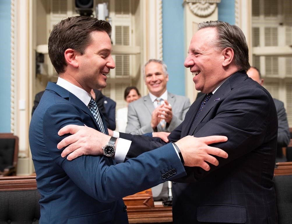 Quebec Minister of Immigration, Diversity and Inclusiveness Simon Jolin Barrette, left, is congratulated by Quebec Premier Francois Legault.