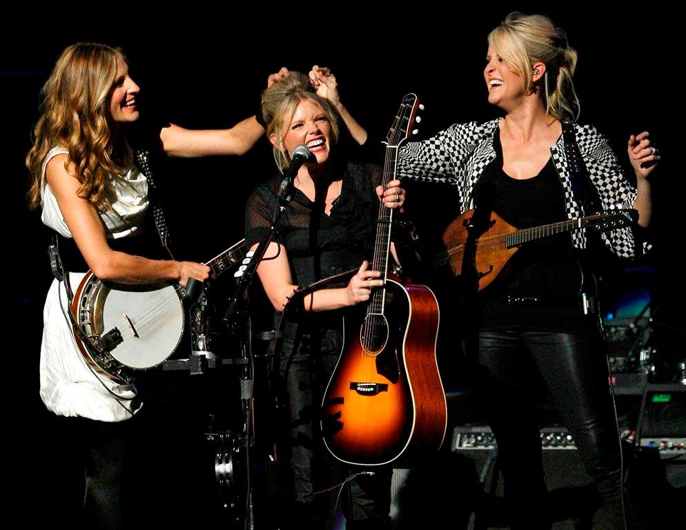 FILE – In this Oct. 18, 2007 file photo, Emily Robison, left, and Martie Maguire, right, adjust Natalie Maines’ hair as the Dixie Chicks perform at the new Nokia Theatre in Los Angeles. (AP Photo/Gus Ruelas, file)