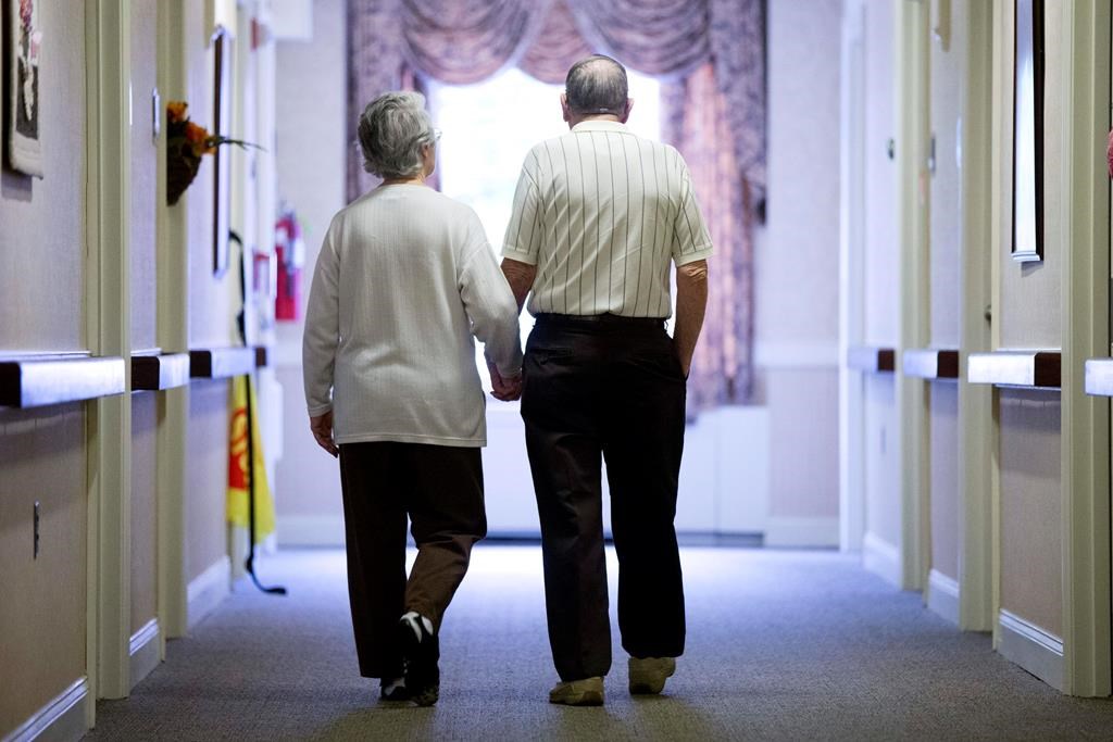 FILE - In this Nov. 6, 2015 file photo, an elderly couple walk down a hall of a nursing home in Easton, Pa.
