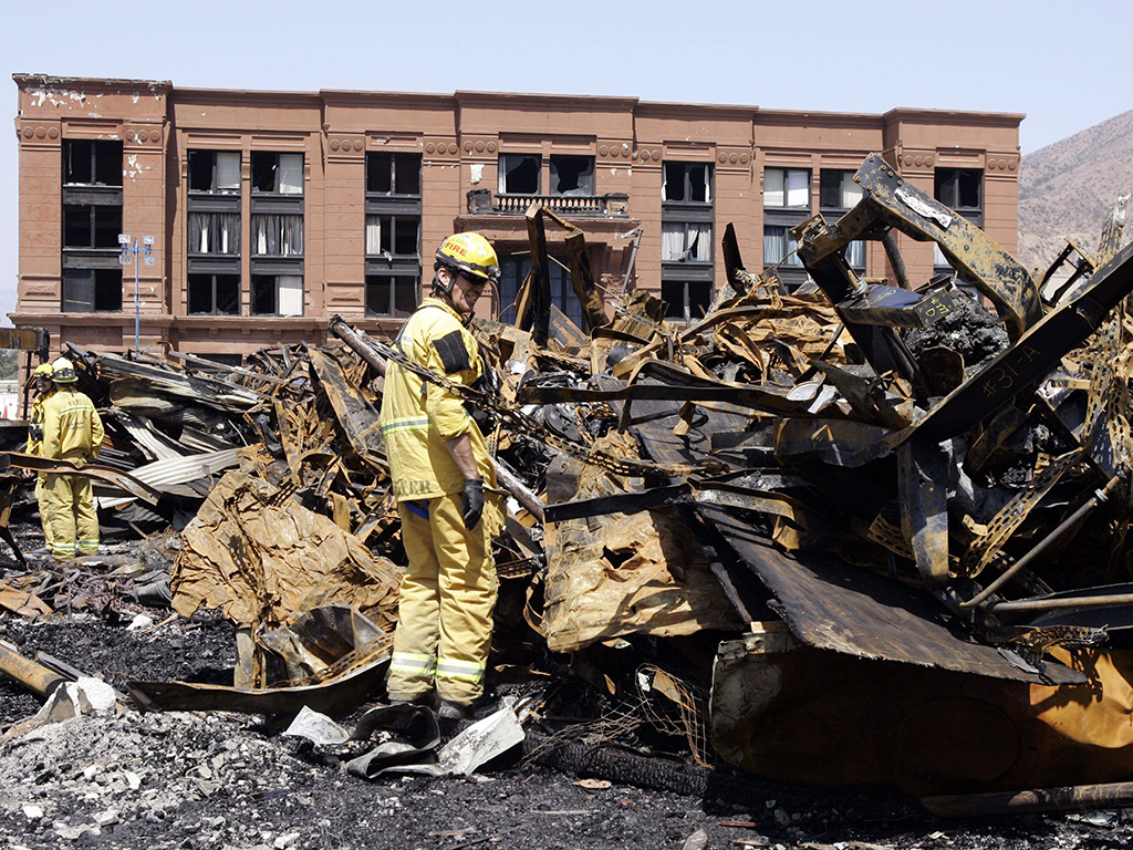 In this June 2, 2008 file photo, Los Angeles County firefighter Darrick Woolever examines metal that needs to be removed at the Universal Studios Hollywood back lot, a day after a fire destroyed the New York Street facade, in the Universal City section of Los Angeles. 