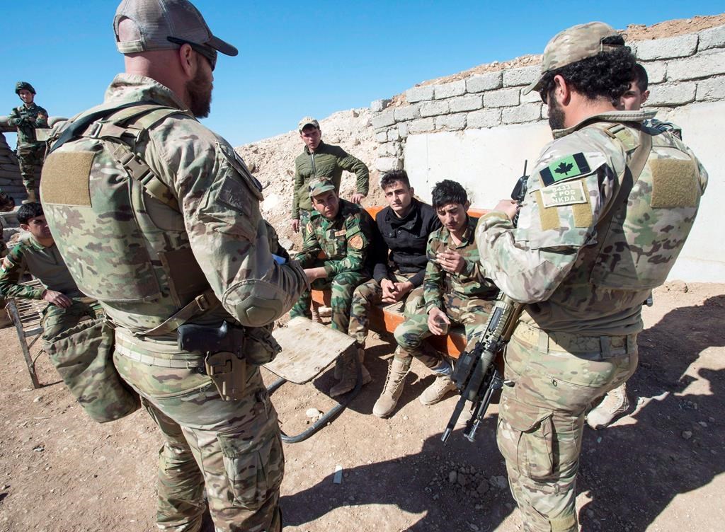 Canadian special forces soldiers, left and right, speak with Kurdish Peshmerga fighters at an observation post, in northern Iraq.