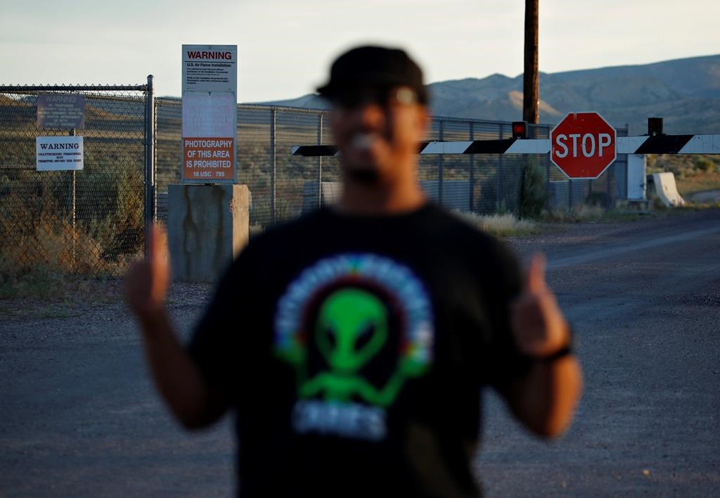 In this July 22, 2019 photo, Stan Evans poses as he has his picture taken while visiting an entrance to the Nevada Test and Training Range near Area 51 outside of Rachel, Nev. The U.S. Air Force has warned people against participating in an internet joke suggesting a large crowd of people “storm Area 51,” the top-secret Cold War test site in the Nevada desert. (AP Photo/John Locher)
