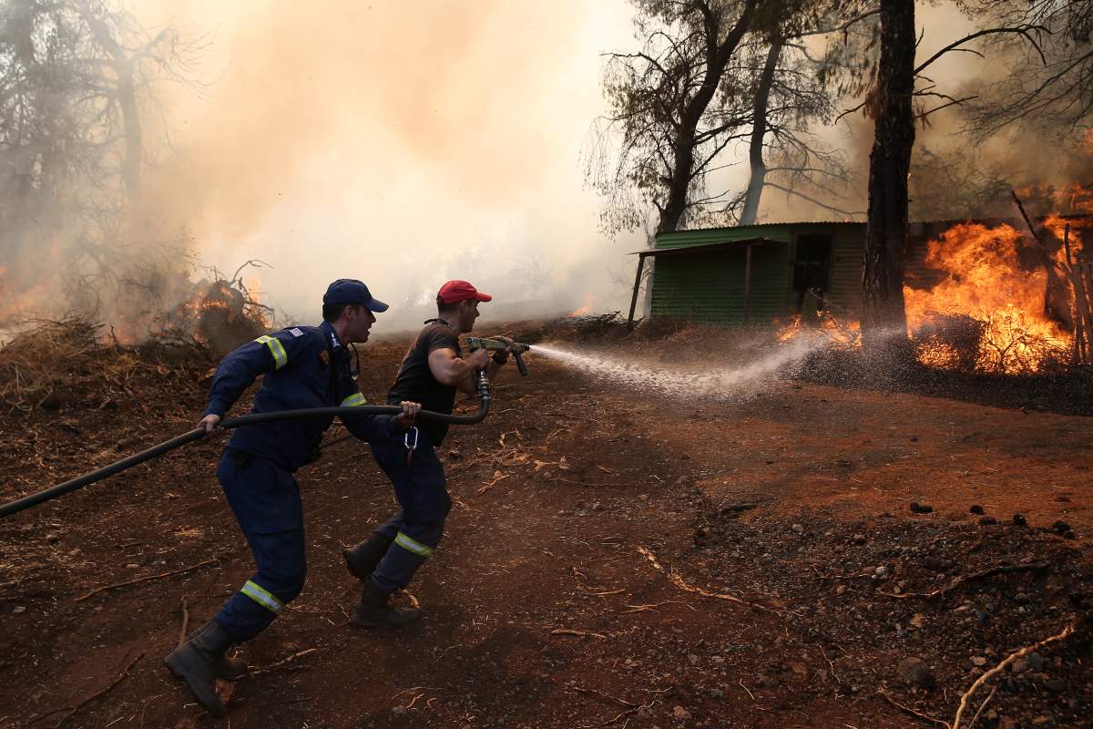Firefighters try to extinguish a wildfire burning in village of Makrimalli on the island of Evia, Greece, Aug. 14.