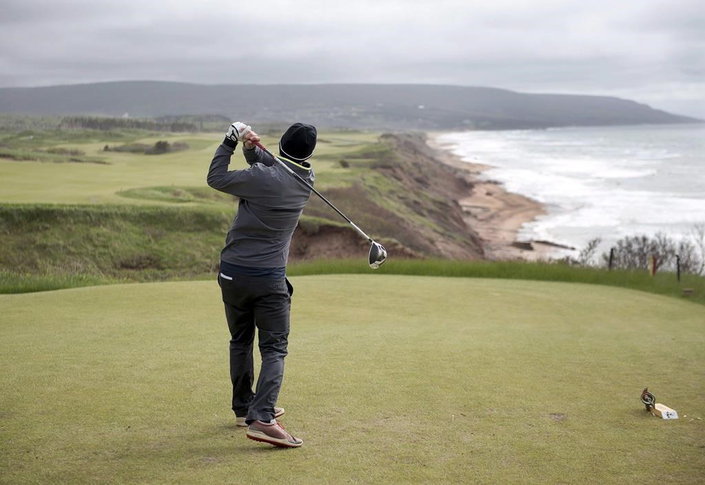 A golfer hits from the tee on the 528 yard, par 5, 18th hole at Cabot Cliffs, the seaside links golf course in Inverness, N.S. on June 1, 2016.