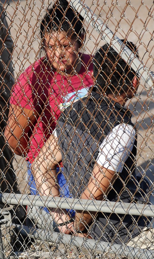 A handcuffed woman stares though the chain link fencing at Koch Foods Inc., in Morton, Miss., Wednesday, Aug. 7, 2019.