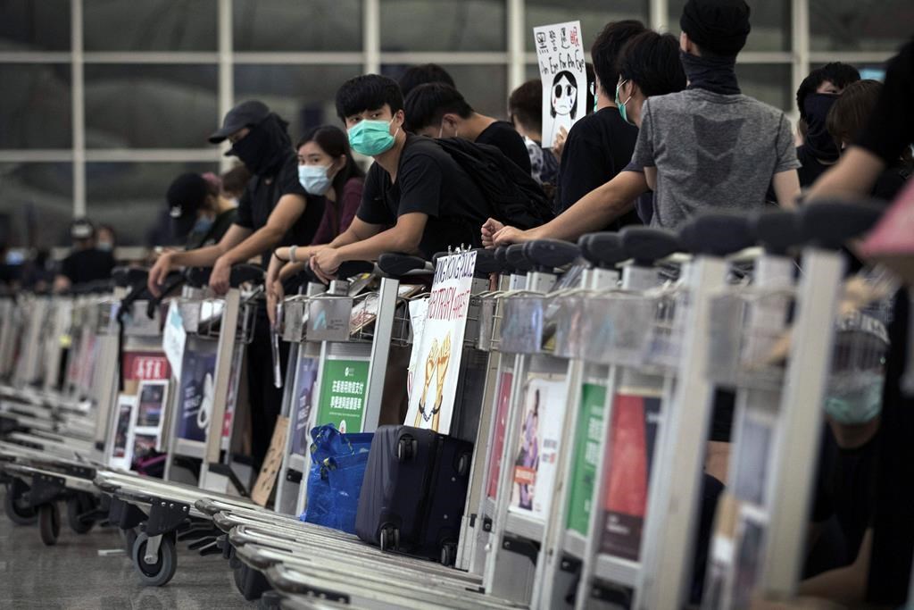 Protesters use luggage trolleys to block the departure gates during a demonstration at the Airport in Hong Kong, Tuesday, Aug. 13, 2019.