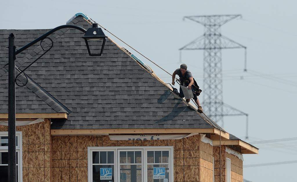 A construction worker shingles the roof of a new home in a housing development in Ottawa on Monday, July 6, 2015.