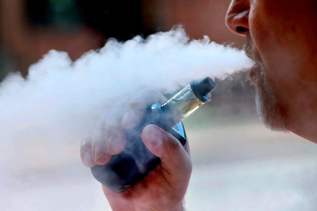 FILE - In this Aug. 28, 2019, file photo, a man exhales while smoking an e-cigarette in Portland, Maine.
