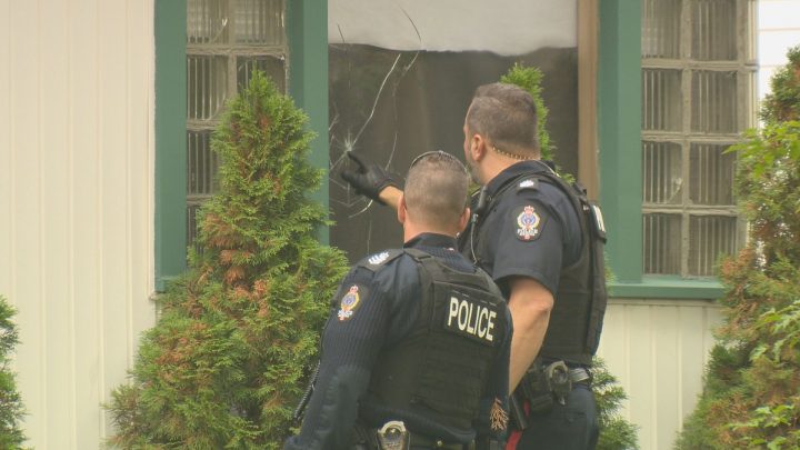 Regina police officers investigate a broken window caused by what appears to be a bullet on Sept. 3, 2019.