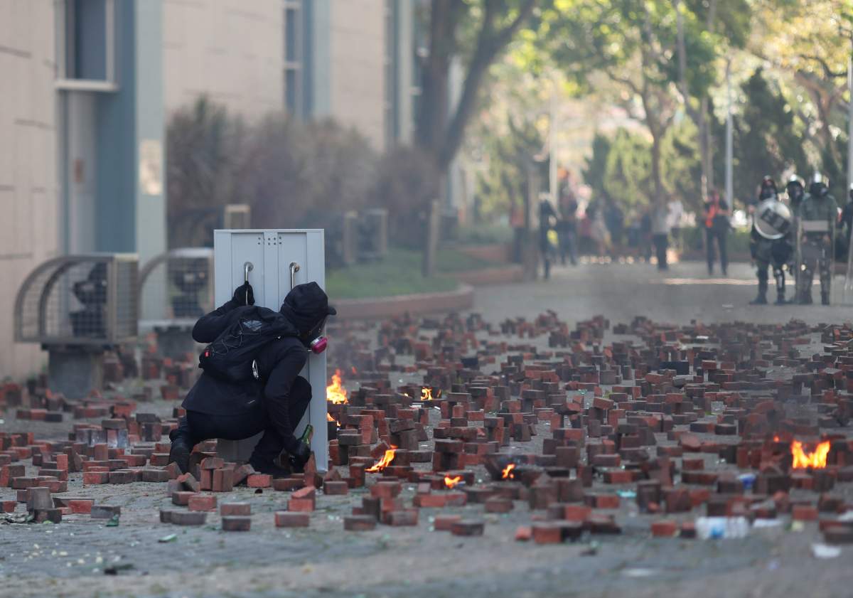 A protester hides behind a shield during clashes with police outside Hong Kong Polytechnic University in Hong Kong, China on Nov. 17, 2019. (REUTERS/Adnan Abidi)