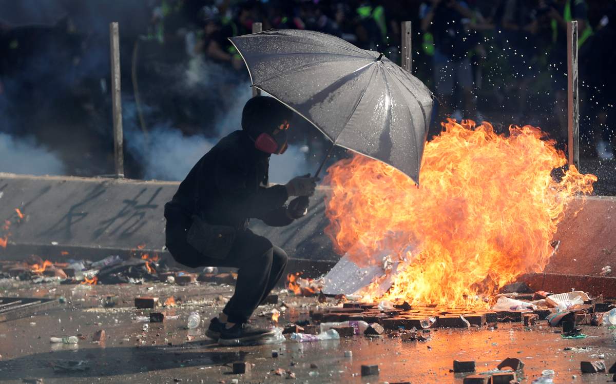 A protester takes cover under an umbrella during clashes with police outside Hong Kong Polytechnic University (PolyU) in Hong Kong, China on Nov. 17, 2019. (REUTERS/Adnan Abidi)