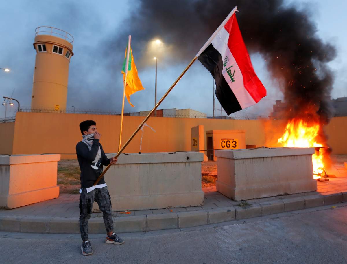 A protester holds an Iraqi flag during a protest to condemn air strikes on bases belonging to Hashd al-Shaabi (paramilitary forces), outside the main gate of the U.S. Embassy in Baghdad, Iraq December 31, 2019.