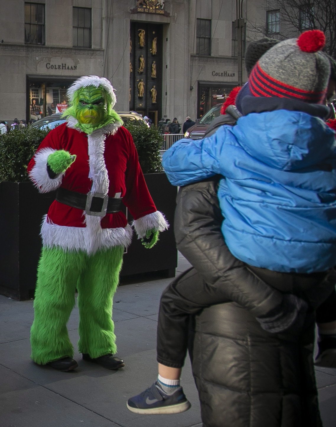 In this Dec. 20, 2019 photo, a costumed Grinch performer, left, works a sidewalk poses for a photo along 5th Avenue near Rockefeller Center in New York.