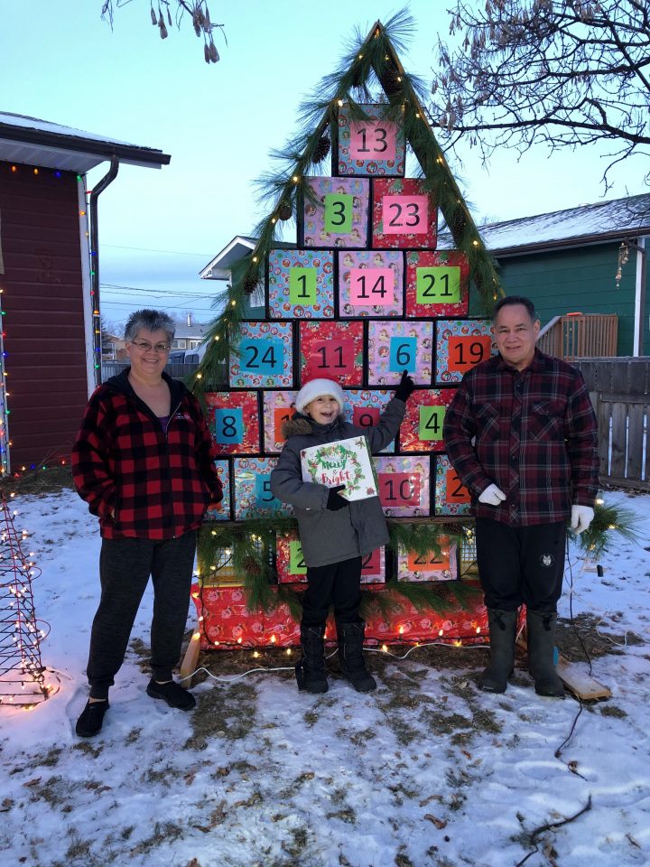 Brenda Morin, her grandson Chance Hodgson and her husband Harold stand in front of their calendar.
