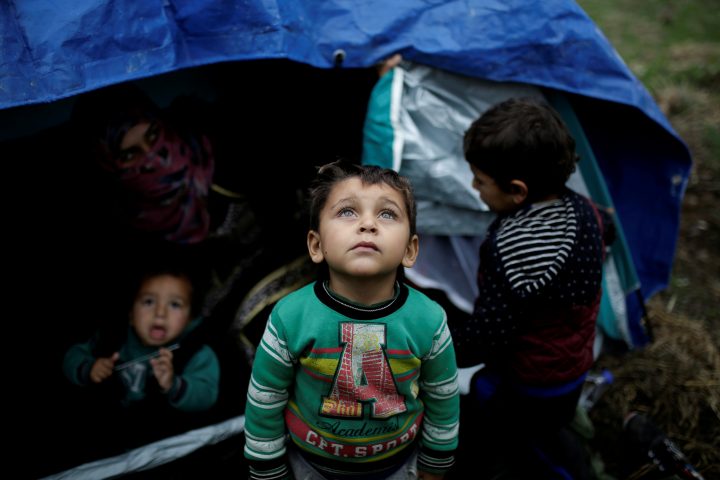 A Syrian refugee boy stands in front of his family tent at a makeshift camp for refugees and migrants next to the Moria camp on the island of Lesbos, Greece, Nov. 30, 2017. 