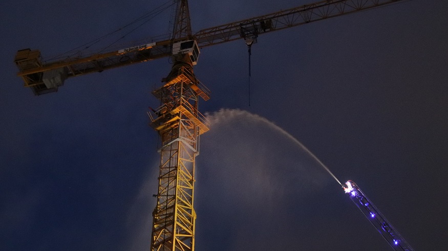 Fire crews use an aerial ladder to direct water streams at a construction crane cabin that caught fire in Coquitlam on Jan. 29, 2020.