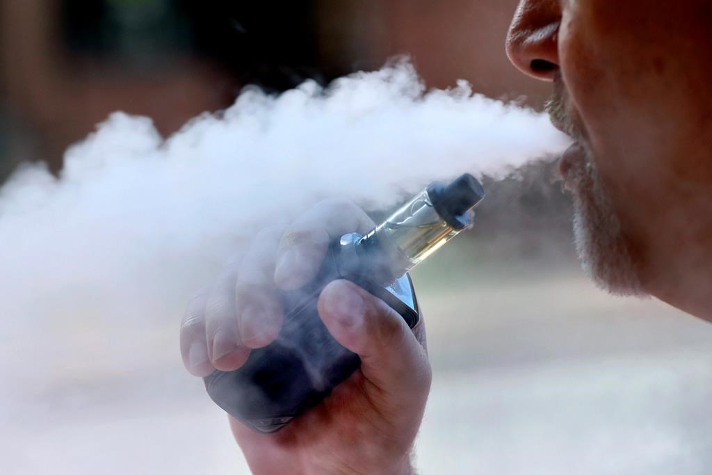 In this Aug. 28, 2019 photo a man exhales while smoking an e-cigarette in Portland, Maine. Alberta is reporting its first case of a severe vaping-associated lung illness.