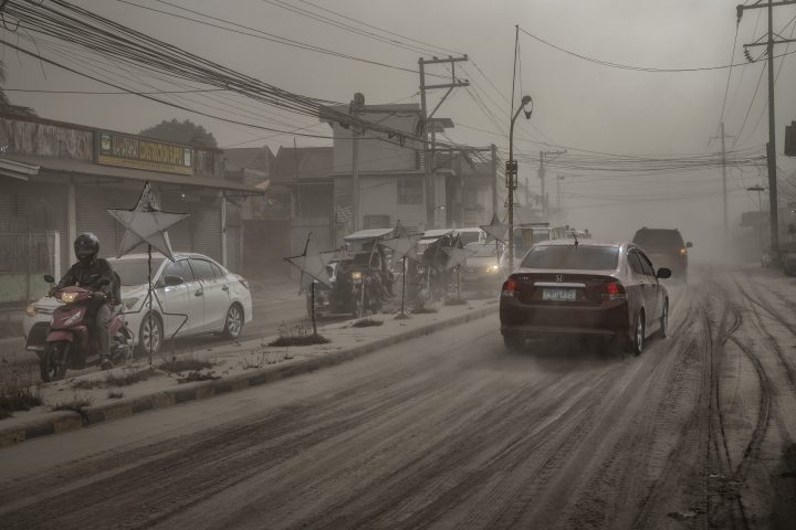 Motorists drive through a road covered in volcanic ash from Taal Volcano’s eruption on Jan. 13, 2020 in Lemery, Batangas province, Philippines.